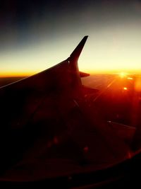 Airplane wing against sky during sunset