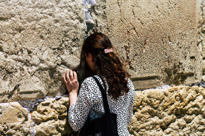 Young woman standing on rock in winter