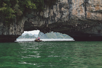 People rowing boat on halong bay under rock formation