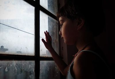 Side view of woman looking through window