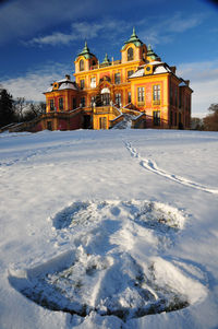 Snow covered houses by building against sky