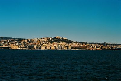 View of townscape by sea against clear sky