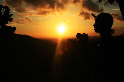 Silhouette of man photographing sunset