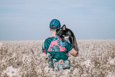 Man with dog standing by blooming flowers