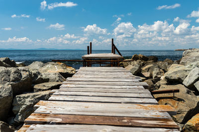 An old, wooden jetty over the beautiful black sea in bulgaria, standing on a stony shore,