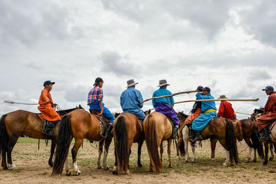 Group of people riding horses on land against sky