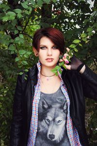 Portrait of hipster woman against tree