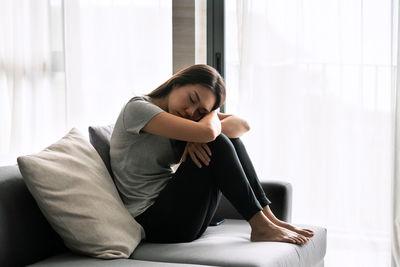 Young woman sitting on sofa at home