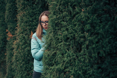 Portrait of young woman standing against plants