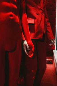 Midsection of man holding red while standing in bedroom