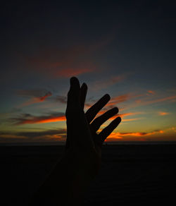 Silhouette woman with arms raised against sky during sunset