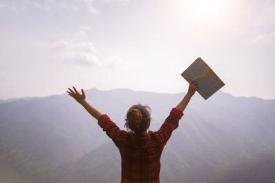 Low angle view of man with arms raised standing against sky