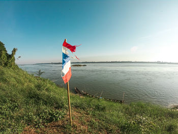 Scenic view of flag on beach against sky