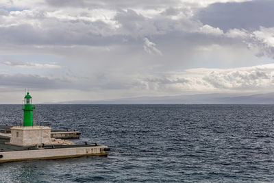 Lighthouse by sea against sky