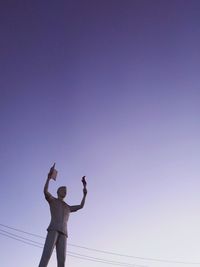 Low angle view of woman standing against clear blue sky