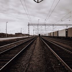 Railroad tracks by freight train against sky