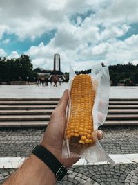 Midsection of person holding ice cream against sky