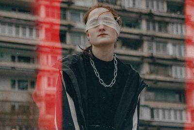 Close-up of woman with blindfold standing against building