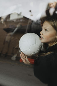 Girl with soccer ball day dreaming seen through glass of car