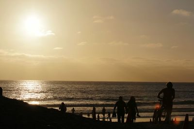 Silhouette people on beach against sky during sunset