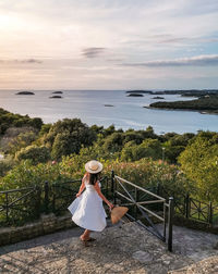 Young woman on a lookout terrace over sea. white dress, viewpoint, nature, sea, vacation.