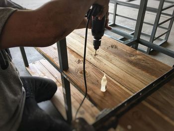 Midsection of man drilling in wood