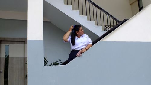 Teenage girl in school uniform standing on staircase of building