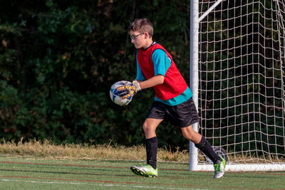 Full length of a boy playing goalie in a soccer game on grass
