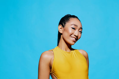 Young woman looking away against blue background