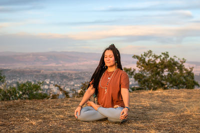 Young woman is sitting in the lotus position and meditating on mountain top. 
