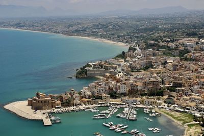 High angle view of townscape seaport by sea against sky with azur blue water in sicily