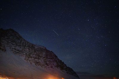 Low angle view of snowcapped mountain against star field sky at night