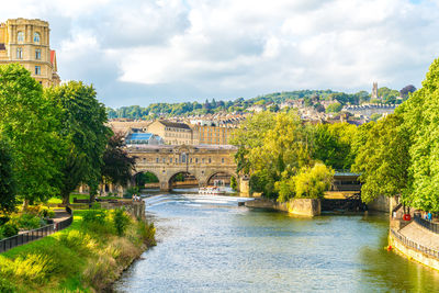 Arch bridge over river amidst buildings against sky