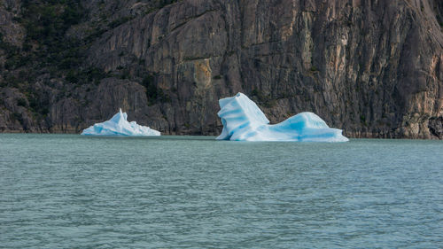 Scenic view of icebergs in sea against mountain