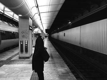 Rear view of woman standing on railroad station platform