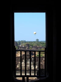 Landscape seen through glass window against clear sky