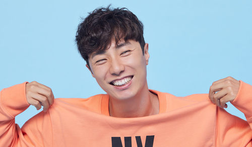 Portrait of smiling young man against blue background