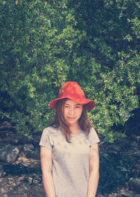 Portrait of smiling young woman standing against plants