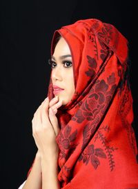 Portrait of beautiful young woman against black background