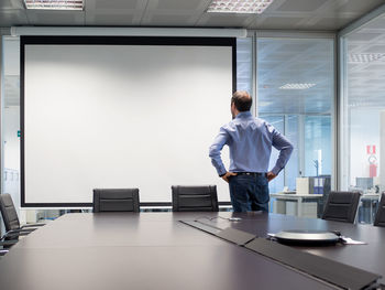 Businessman standing by projection screen in board room at office