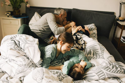 High angle view of happy family enjoying with each other on bed at home