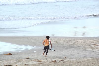 Rear view of boy walking on beach