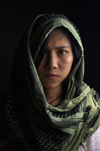 Close-up portrait of young woman against black background