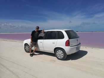 Man standing on car against sky