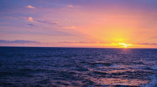 Scenic view of sea against dramatic sky during sunset