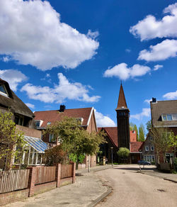 Houses by street amidst buildings against sky in city