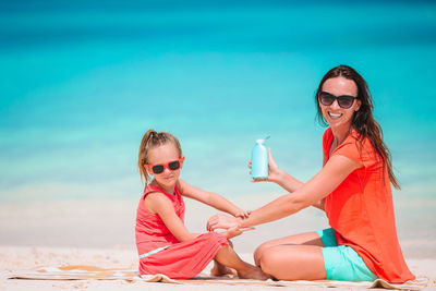 Portrait of mother and daughter sitting at beach