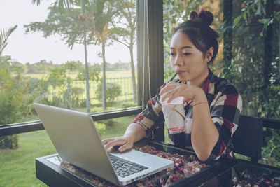 Young woman using mobile phone while sitting on table