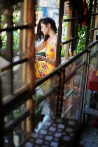 Side view of woman looking away while standing on window