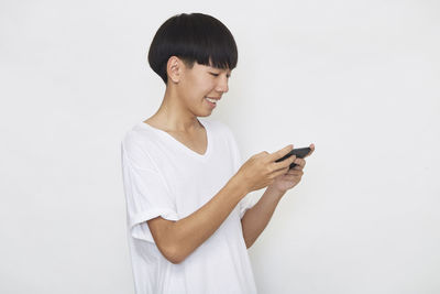 Young man using mobile phone against white background